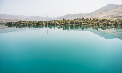 Panorama in nature, the Vakhsh river in Tajikistan, landscape on a hot summer sunny day in Asia, reflection in the blue mirror water of the river
