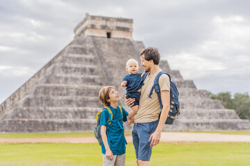 Father and two sons tourists observing the old pyramid and temple of the castle of the Mayan...