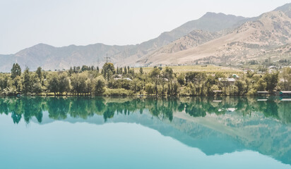 Panorama in nature, the Vakhsh river in Tajikistan, landscape on a hot summer sunny day in Asia, reflection in the blue mirror water of the river