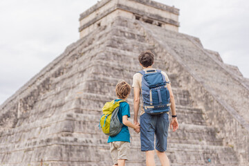 Father and son tourists observing the old pyramid and temple of the castle of the Mayan...