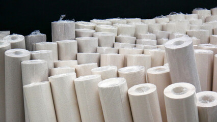 Many rolls of wallpaper standing against a black wall