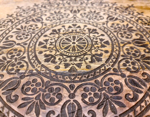 An intricate oriental pattern on a beautiful wooden surface.