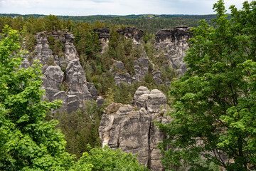 A mountain range with a forest in the background. The trees are green and the sky is cloudy