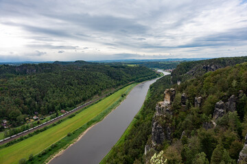 A river runs through a lush green valley. The sky is cloudy, and the river is calm