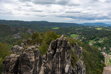 A mountain range with a cloudy sky in the background. The mountains are covered in trees and the sky is overcast