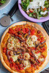 Pizza con productos del mar y bol de ensalada