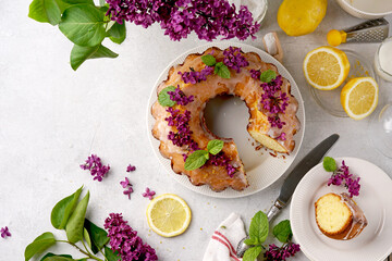 Still life of lemon cake with slice and with lilac on white background. Top view, copy space