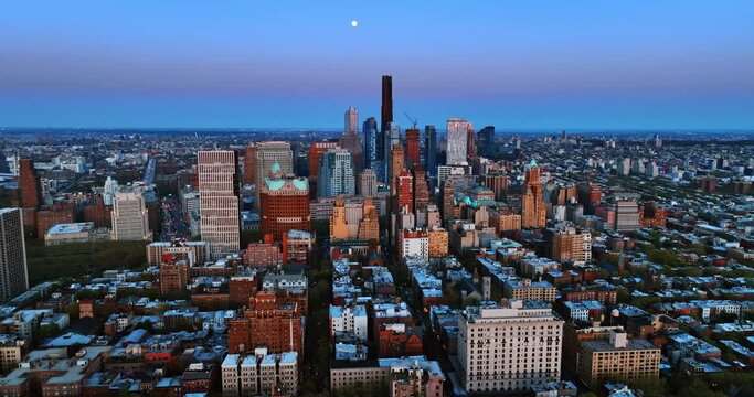 Building of Brooklyn Tower predominates in the scenery of New York. The Moon appeared in the blue sky above the city at dusk.