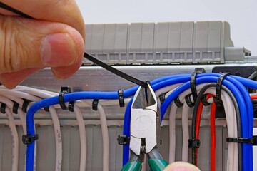 Cutting the cable tie on the insulated mounting wire in the electrical panel.