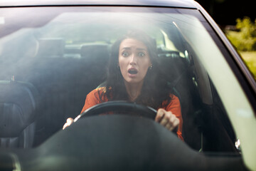 Front view portrait of scared woman driving car before an accident and looking with frightened...