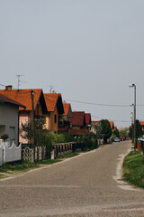 Houses with a tiled roofs in Balkans. Beautiful trees with white flowers blooms in yards. Bijeljina is a small town on the border with Serbia and Bosnia and Herzegovina. A cozy quiet village street.