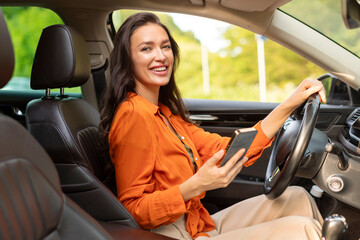 Car navigation app. Happy woman driver using cellphone sitting in automobile and smiling,...