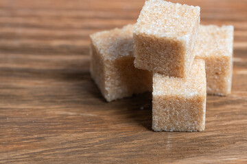 Cubes of refined cane sugar on wooden background.