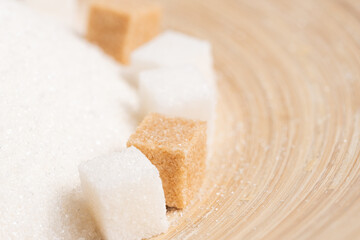 Granulated sugar and refined cane on a wooden background.