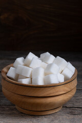 Refined sugar cubes in wooden cup.