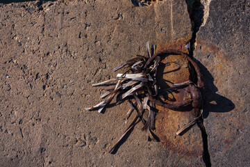 A rusty metal mooring ring has left rusty marks on the concrete in which it is embedded. Remains of dried seaweed hang on the metal
