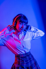 young happy woman listening to music on headphones with neon lights.