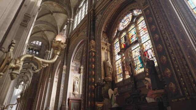 Paris, France - The interior of Saint-Eustache Church in Paris is adorned with Gothic ornaments and architecture, including stained glass windows and intricate Christian sculptures.