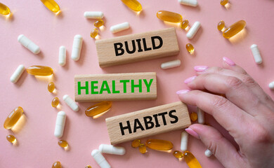 Healthy habits symbol. Concept word Build Healthy habits on wooden blocks. Doctor health. Beautiful pink background with pills. Healthy lifestyle and Healthy habits concept. Copy space