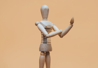 A wooden mannequin of a man bends one arm at the elbow with his fist up in the form of an obscene gesture, fuck you. The concept of a possible conflict between artificial intelligence and humans.