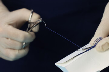 Close up in a surgical need beeing hold by a surgical equipment by a professional wearing sterile gloves 