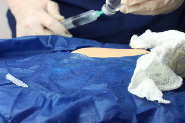 Health care professional wearing gloves injecting a drug in a patient skin during a procedure in a...