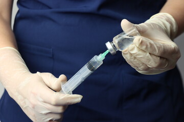 Profissional wearing gloves snorting drug from a vial with a syringe 