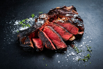 Barbecue dry aged chianina rib of beef steak served with crystal salt and thyme as close-up on a...
