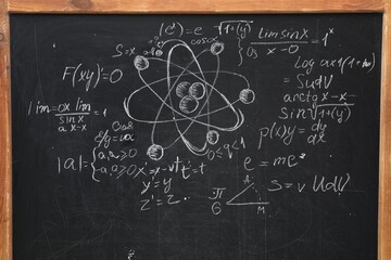 Many different physical formulas written with chalk on blackboard