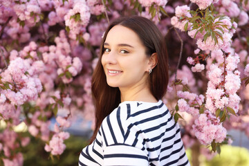 Beautiful woman near blossoming tree on spring day