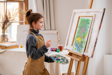 A young girl is painting a picture on a canvas.