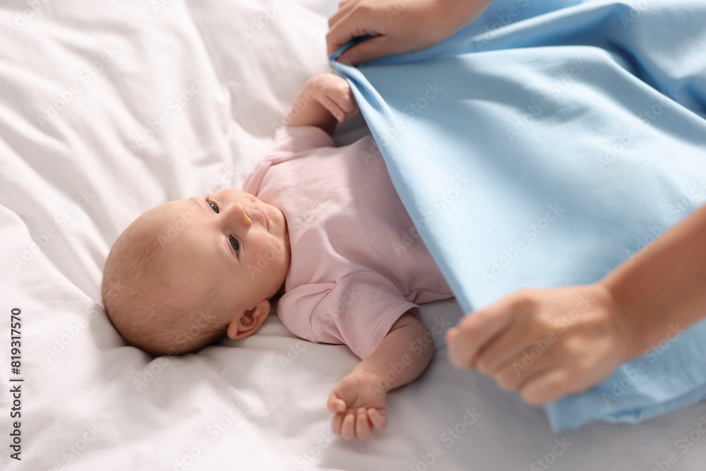 Wall mural Mother with her cute little baby on white sheets