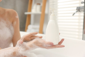Woman taking bath with shower gel in bathroom, closeup