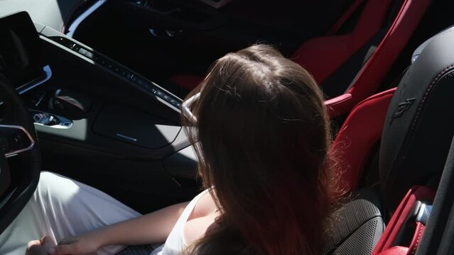 A girl sits behind the wheel of a red car with her hands up, enjoys life, a rich life, a lot of money.. Luxurious car and girl 