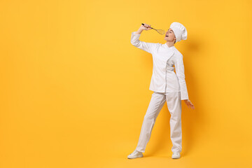 Professional chef with whisk having fun on yellow background. Space for text