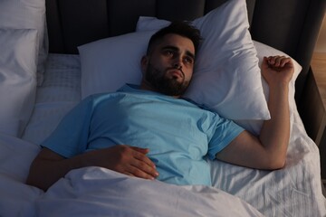 Frustrated man suffering from insomnia in bed