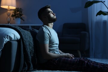 Man suffering from insomnia in bedroom at night