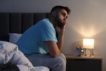 Frustrated man suffering from insomnia on bed