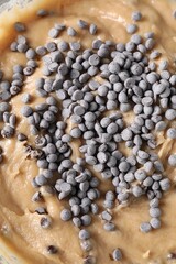 Raw dough with chocolate chips in bowl, top view