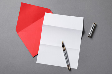 Blank sheet of paper, letter envelope and pen on grey background, top view