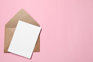 Letter envelope and card on pink background, top view. Space for text