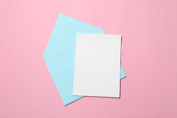 Letter envelope and card on pink background, top view