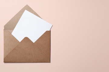Letter envelope with card on beige background, top view. Space for text