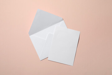 Letter envelope and card on beige background, top view. Space for text