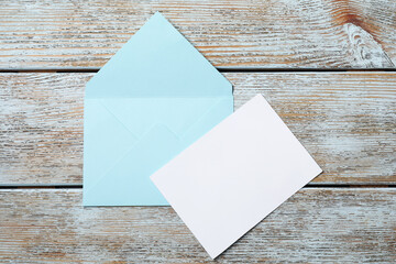 Blank sheet of paper and letter envelope on wooden rustic table, top view. Space for text