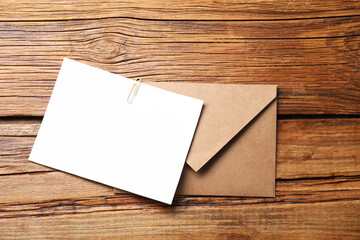 Blank sheet of paper, paperclip and letter envelope on wooden table, top view. Space for text