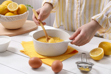 Woman cooking lemon curd at white wooden table, closeup