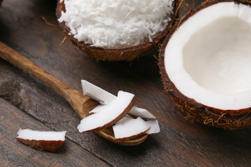 Coconut flakes, spoon and nut on wooden table