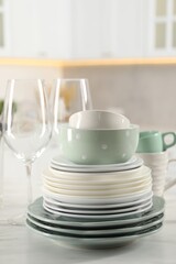 Many different clean dishware and glasses on white marble table in kitchen