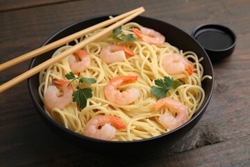 Tasty spaghetti with shrimps, parsley and soy sauce on wooden table, closeup